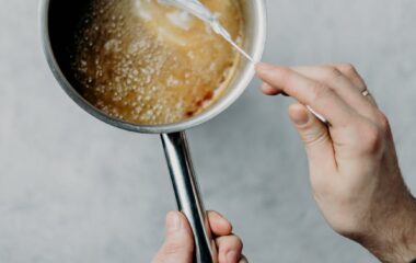 person melting sugar and butter on a sauce pan