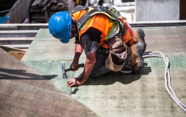 man wearing blue hard hat using hammer