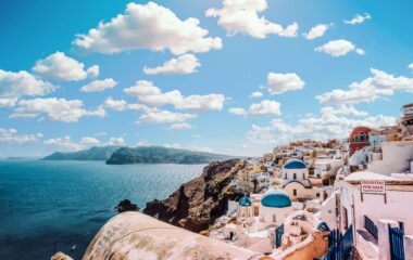 white concrete house near body of water under white and blue cloudy sky