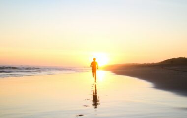 silhouette of boy running in body of water during sunset