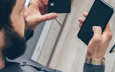 man in gray sweater holding black smartphone